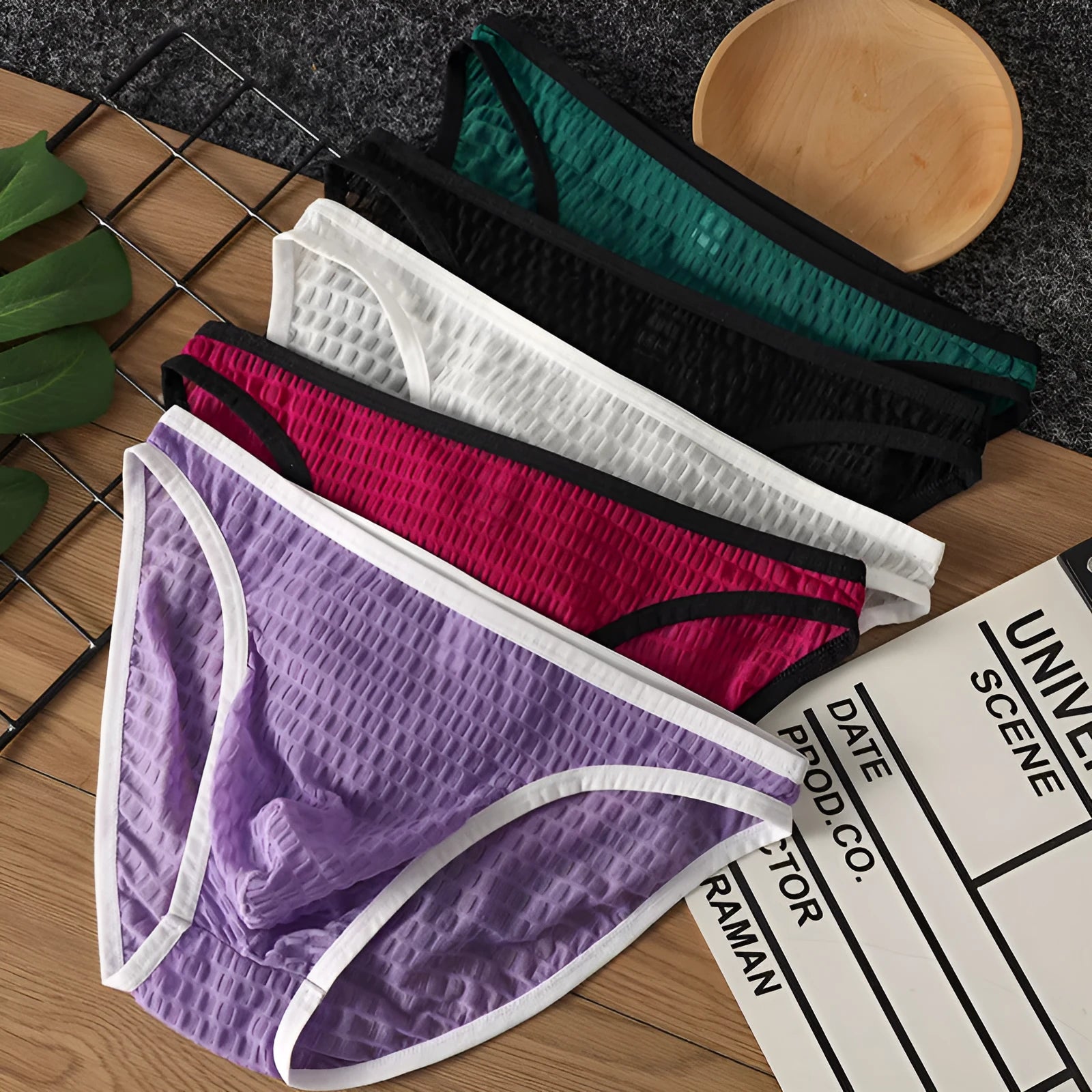 Men's low waist transparent lace underwear in multiple colours on a size chart background.