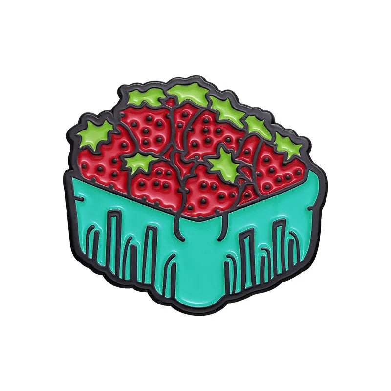 Colourful metal brooch with cartoon fruit and letter design on a blue background.