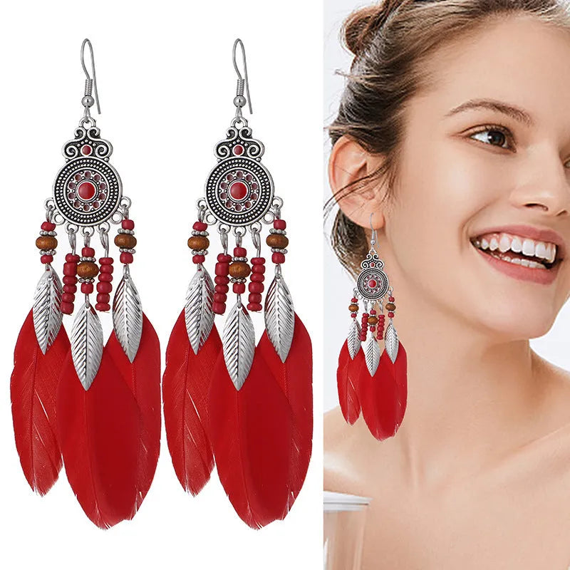 Close-up of a pair of bohemian-style feather and leaf design drop earrings in alloy, showing the electroplated finish.