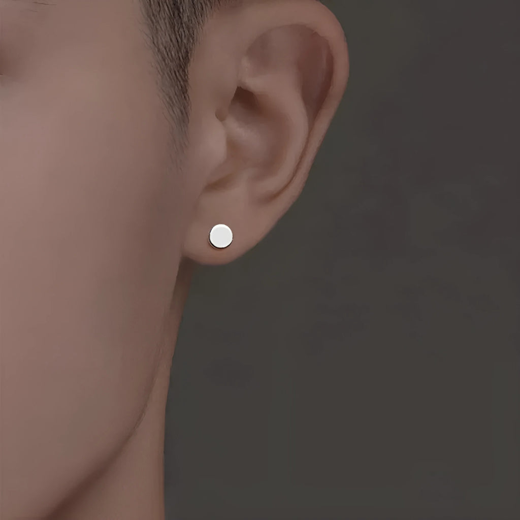 A pair of simple geometric round S999 Sterling Silver flat bone stud earrings in silver and black, showing size variation.