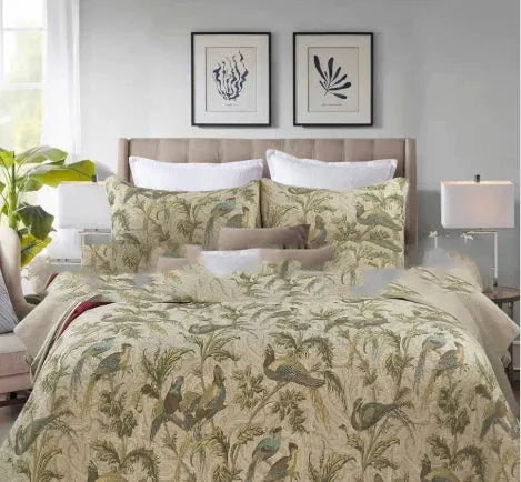 Blue cotton quilted bedspread with detailed floral and bird pattern, shown on a bed.