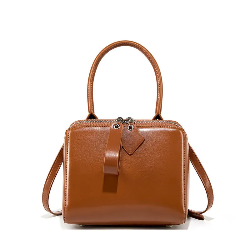 Open grain leather handbag in black with visible grain texture and welt pocket on front