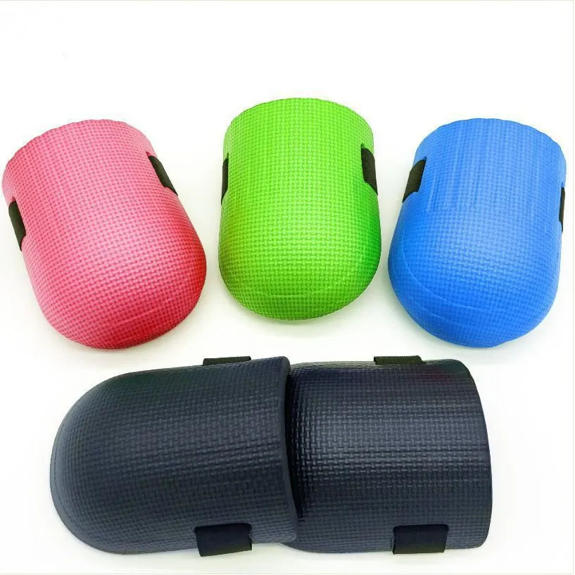 A pair of EVA foam kneepads in black, shown on a hard floor surface.