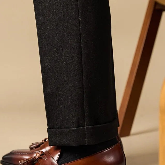 Men's black polished leather tassel loafers with a rubber sole on a white background.