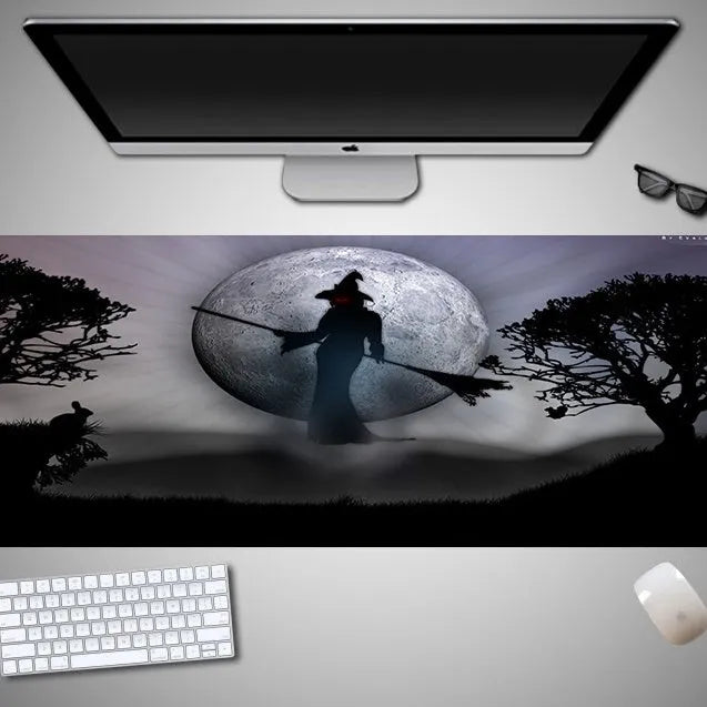 Oversized black Halloween-themed mouse pad with spooky artwork on a desk next to a gaming mouse.