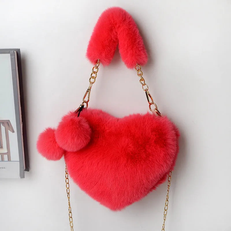 A soft, heart-shaped plush handbag for women in a medium size with a detachable shoulder strap.