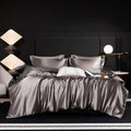 Silk bed sheet four-piece set in solid colour folded, showing options for Ash Purple, Cool Black, and Golden Camel.