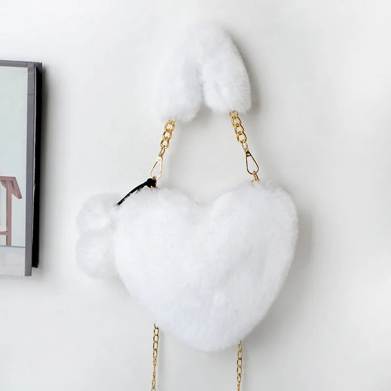 A soft, heart-shaped plush handbag for women in a medium size with a detachable shoulder strap.