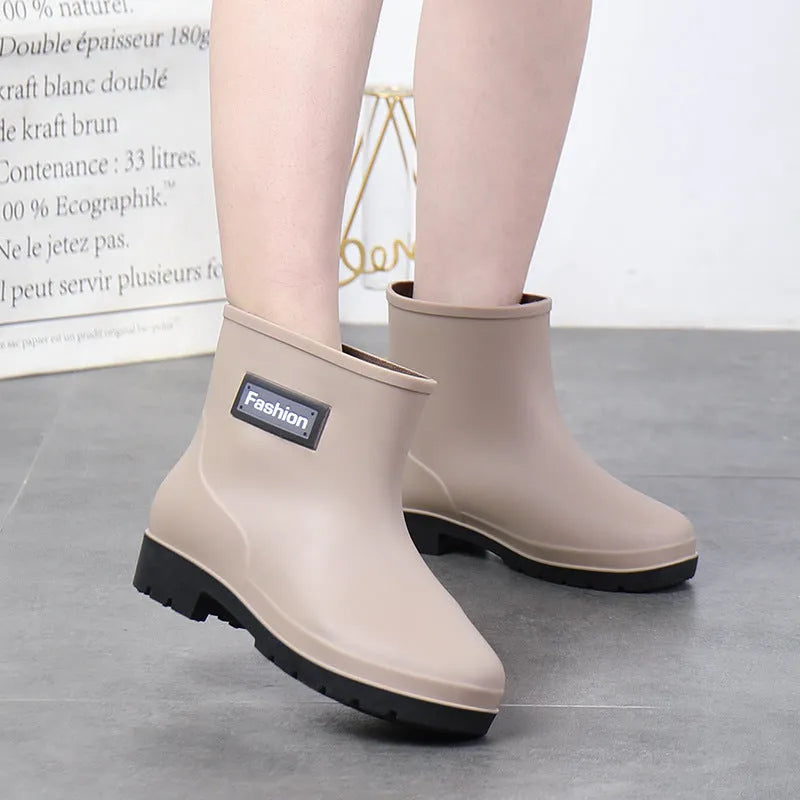 Women's mid-calf PVC rain boot in black on a wet surface, showing low heel and clean design.