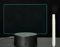 Black 3D LED handwritten acrylic message board with remote control on a desk.