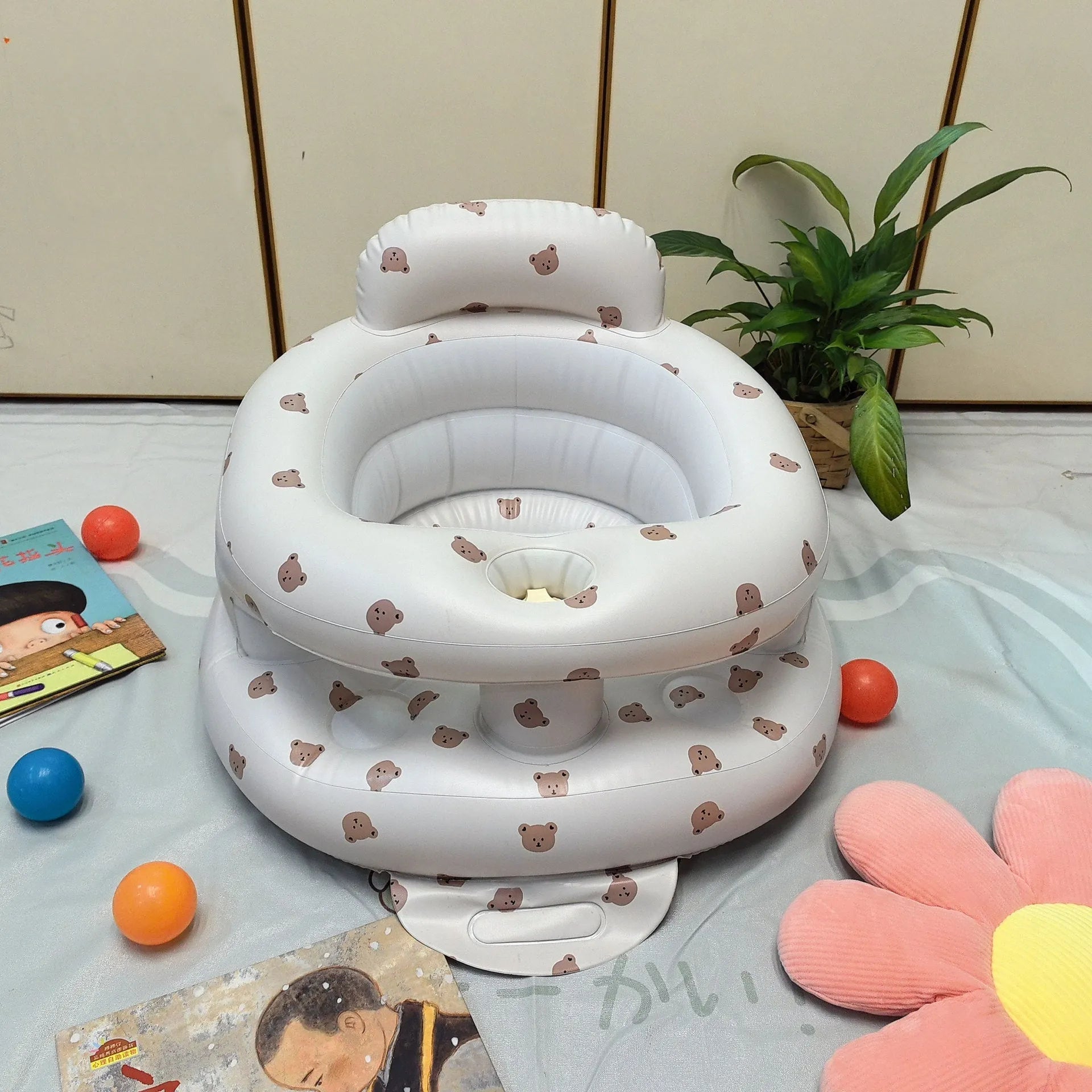 Inflatable infant dining chair in PVC with bear design, deflated beside a baby for scale
