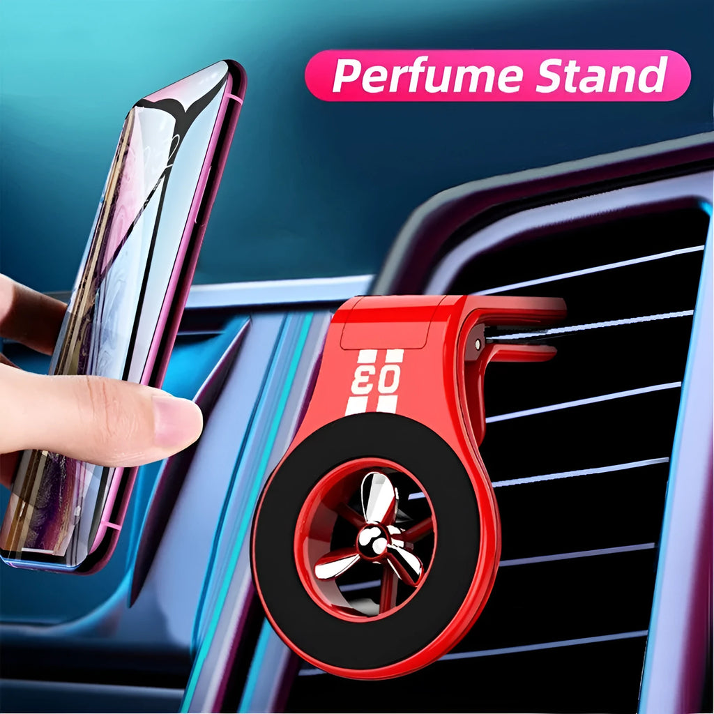 Black magnetic car phone holder clipped to a car air vent, showing adjustable paddle and fragrant slice.