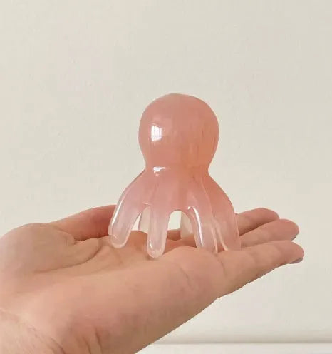 Pink natural resin octopus-shaped massage comb for facial and body meridian therapy.
