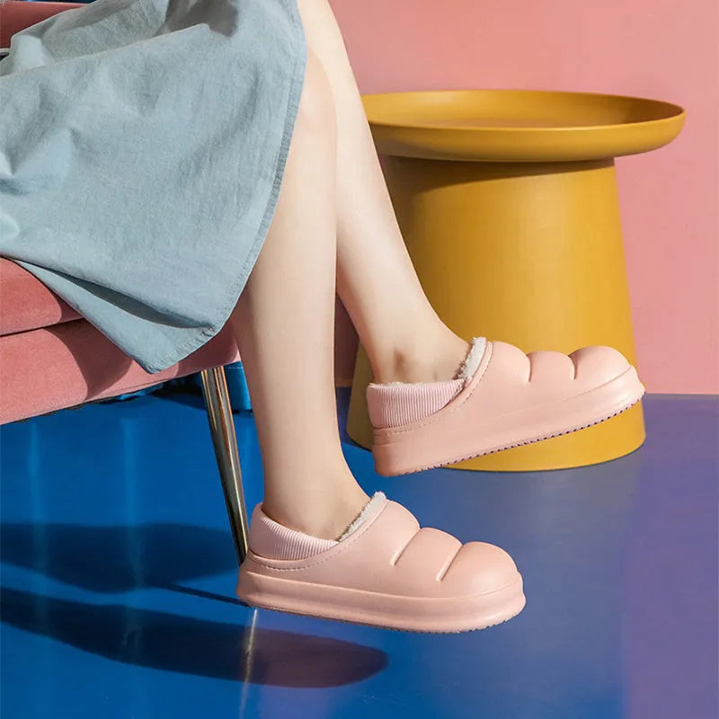 Green waterproof EVA garden slippers with plush lining and a non-slip sole, shown on a wooden deck.