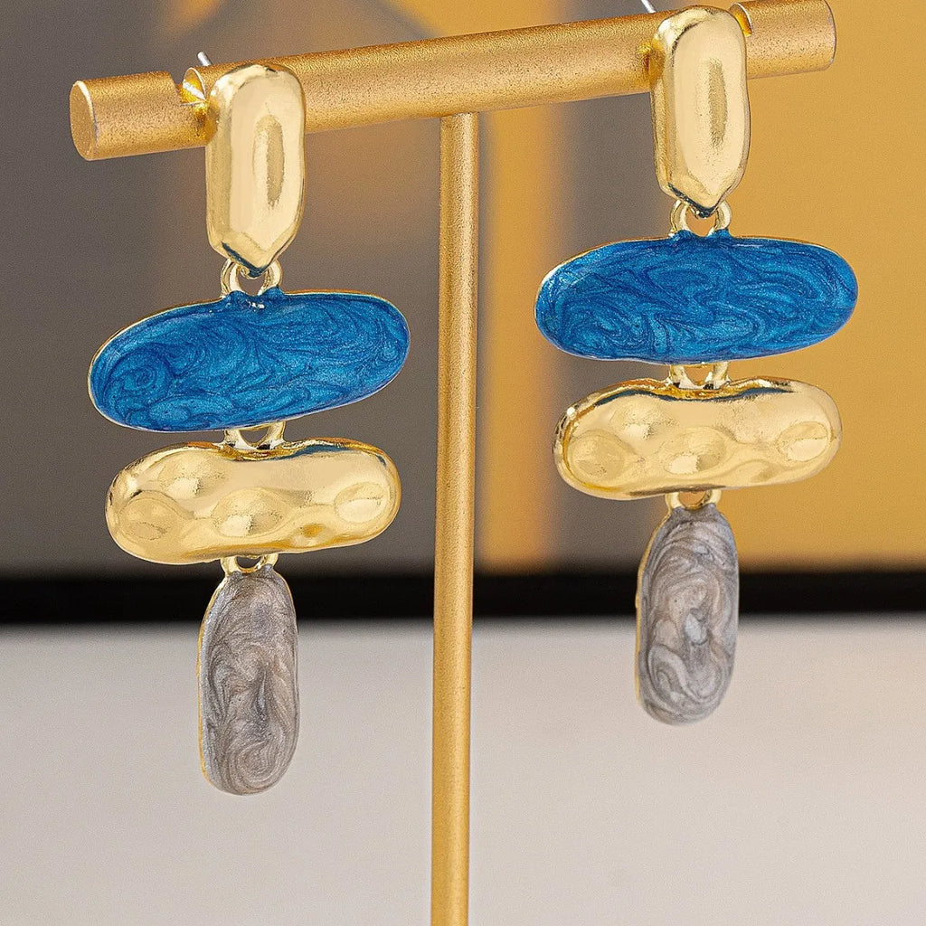 A pair of simple geometric stud earrings with a multicolour electroplated finish on a white background.