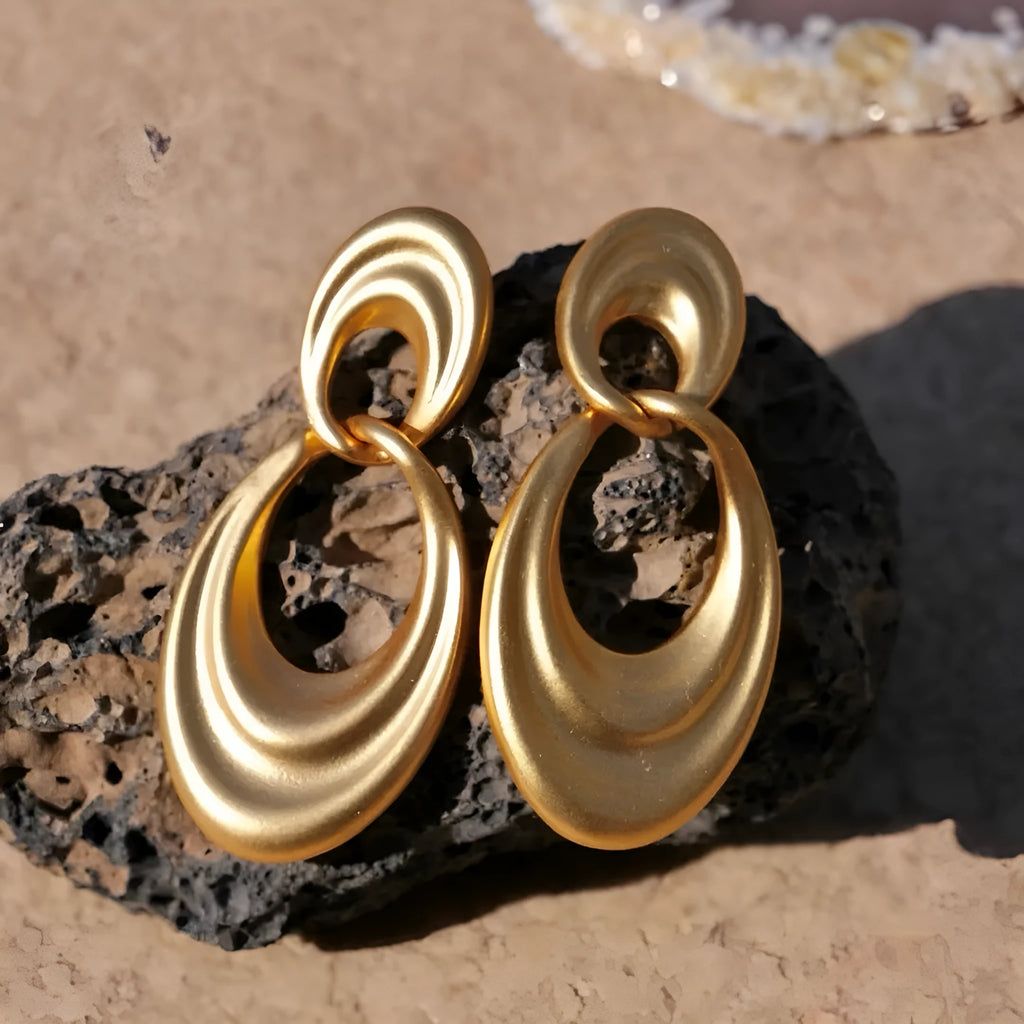 Pair of quicksand gold copper earrings showing a U-shaped design with a double circle detail.