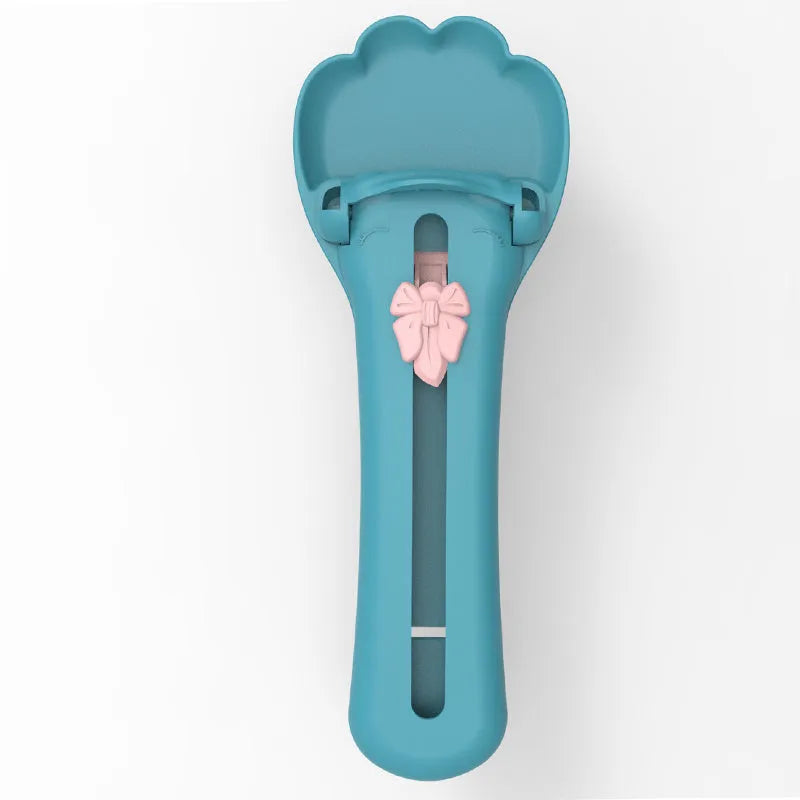 Green and pink pet food squeezer scoop dispensing a treat for a cat or dog.
