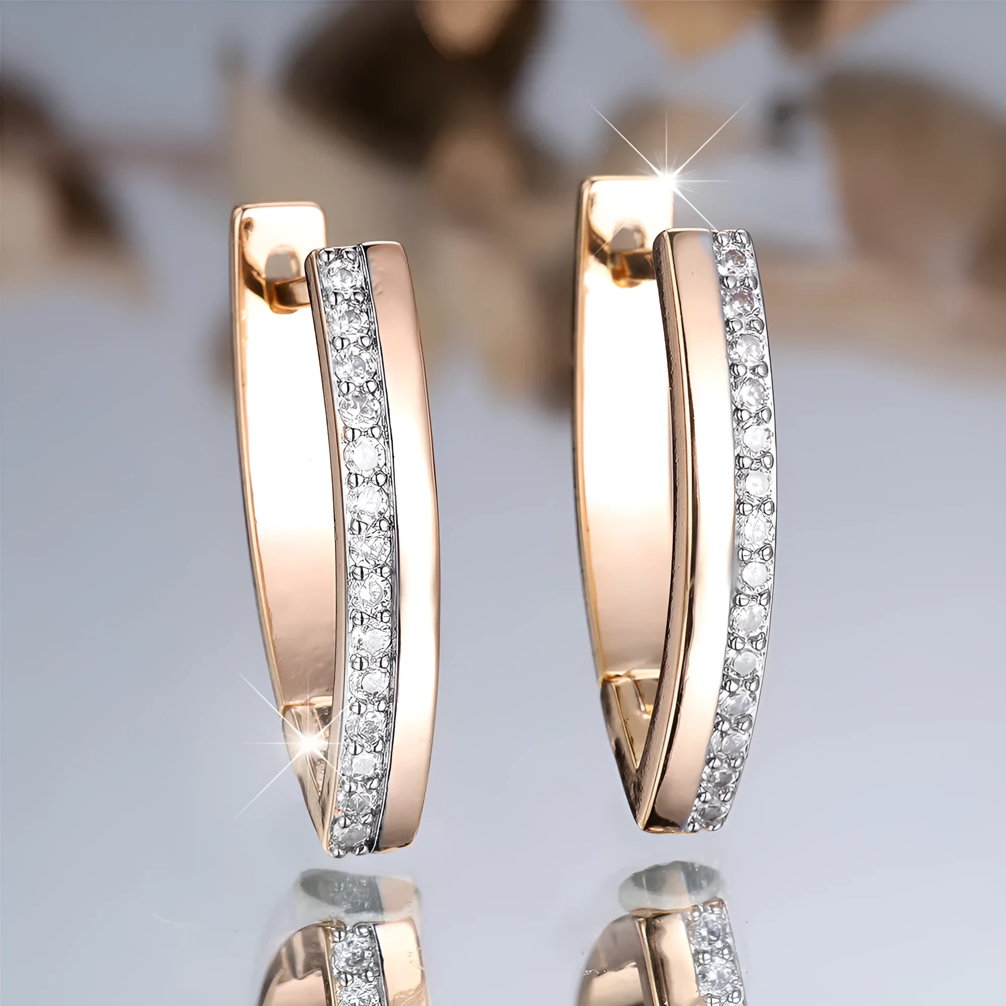 Close-up of women's geometric V-shaped clip-on earrings in champagne gold with white diamond details on a copper base.