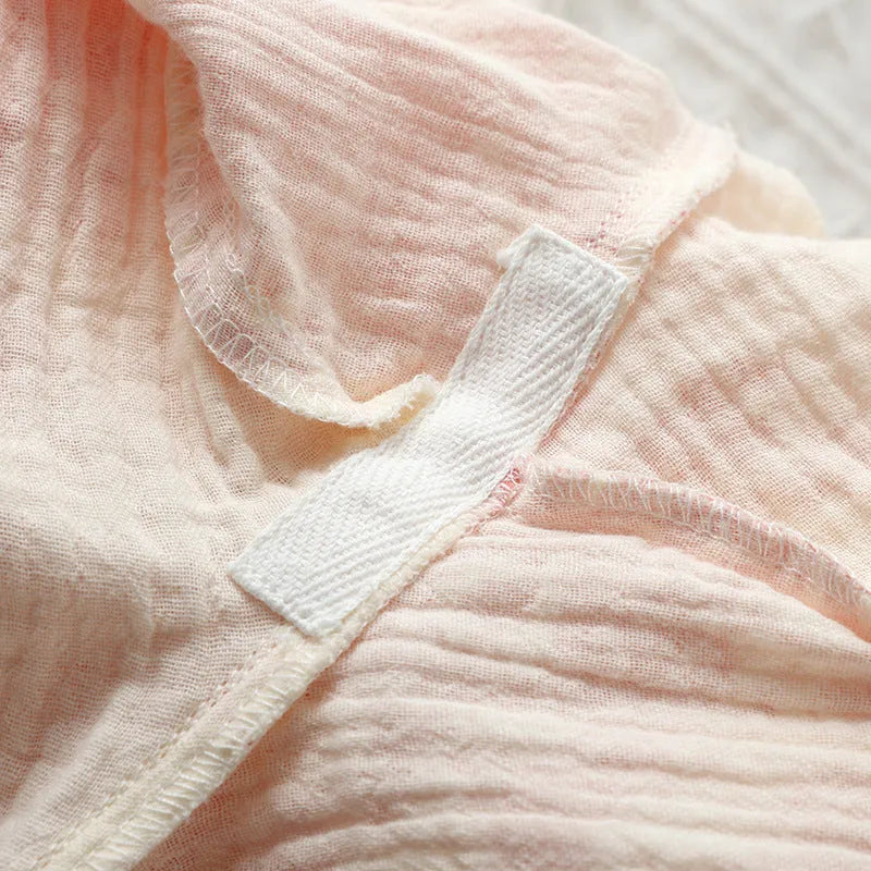 Women's pink pure cotton gauze long sleeve pyjama set with lace-up trousers laid flat.