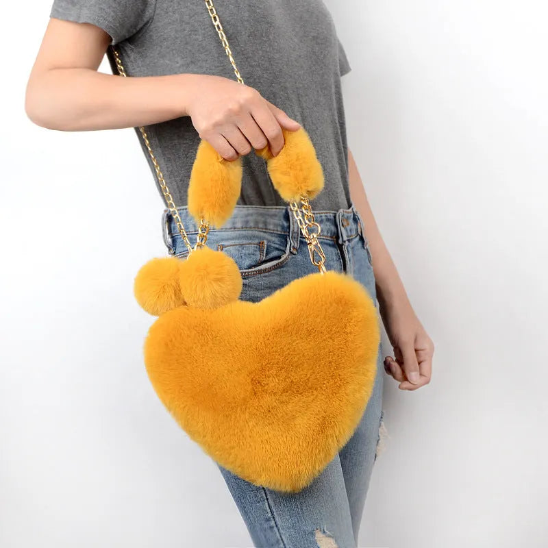 A soft, heart-shaped plush handbag for women in a medium size with a detachable shoulder strap.