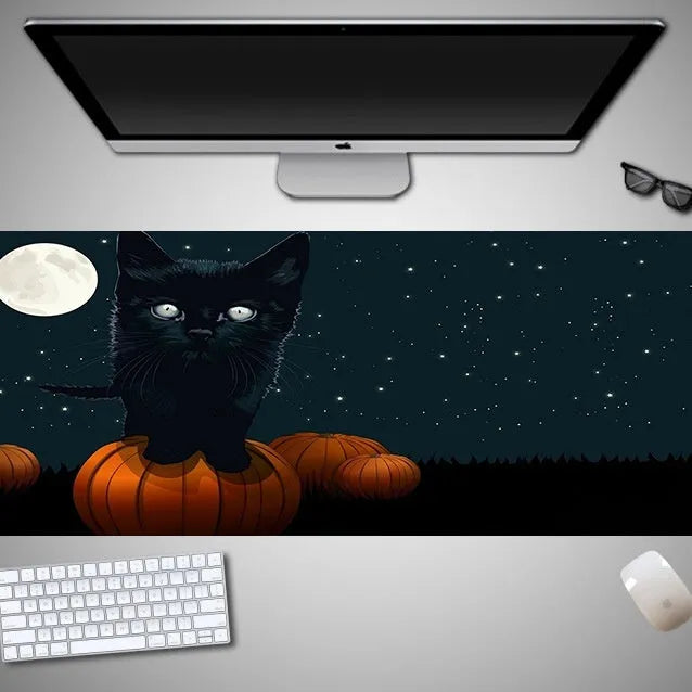 Oversized black Halloween-themed mouse pad with spooky artwork on a desk next to a gaming mouse.