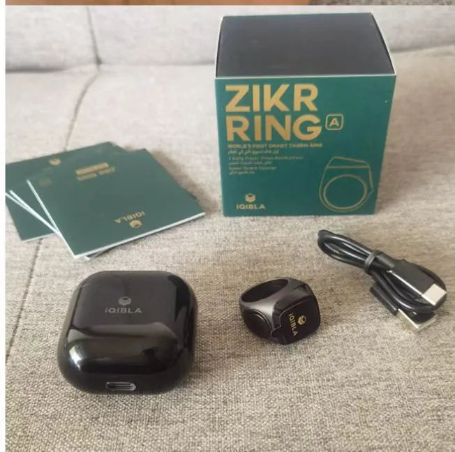 Silver smart ring with a small OLED screen displaying numbers, shown next to its charging case.