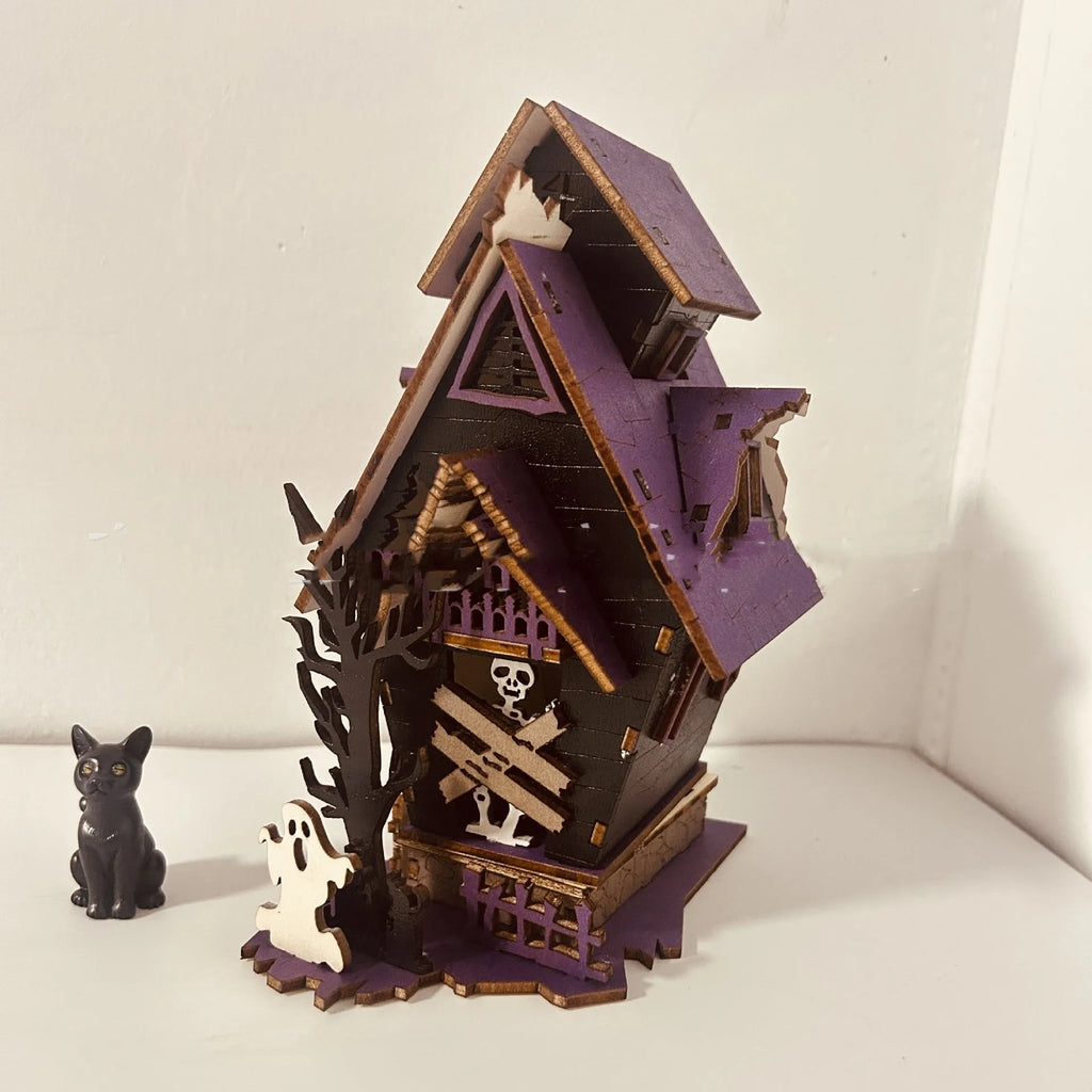 Wooden glowing haunted house Halloween table decoration on a dark surface