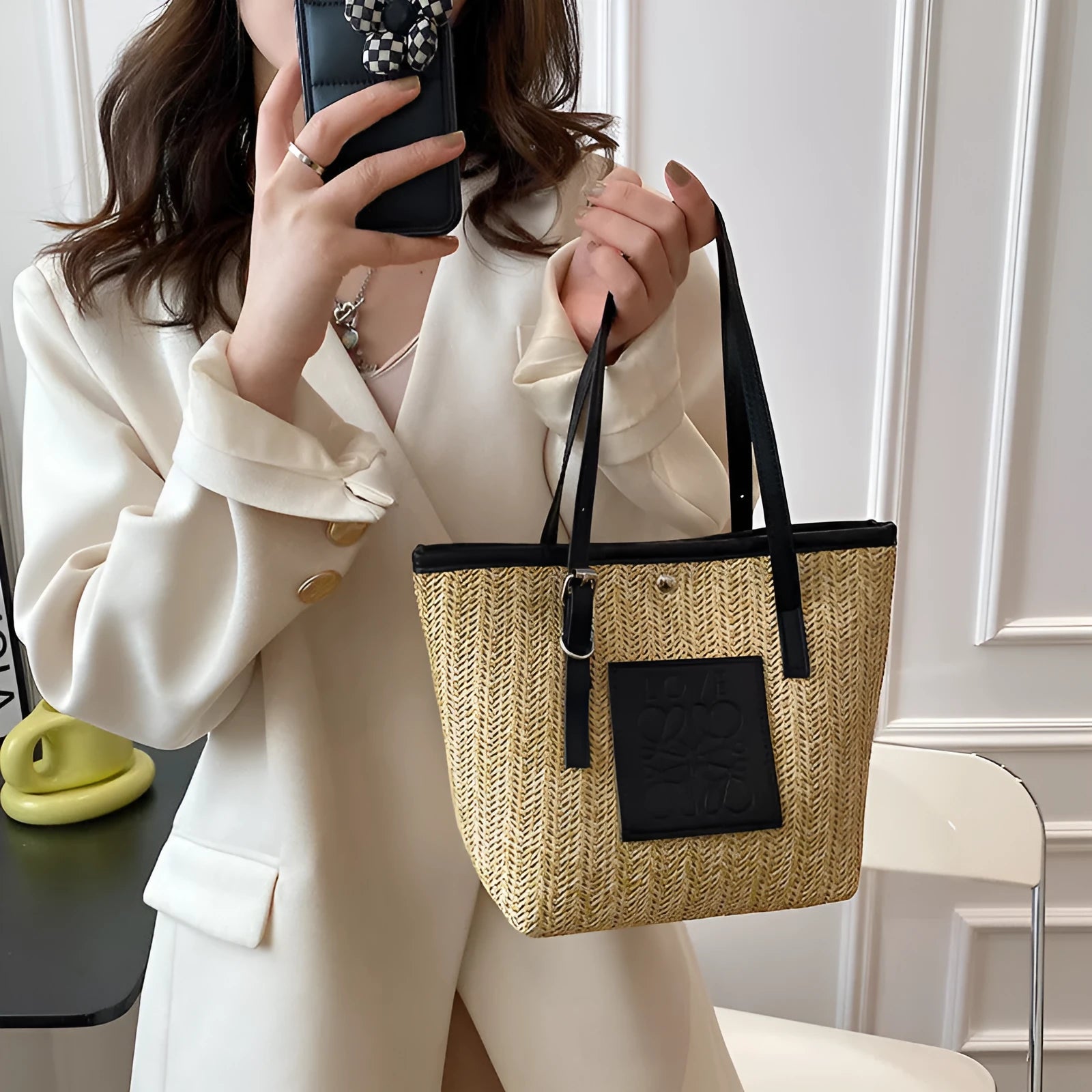 Women's straw woven shoulder bag with PU trim showing tapered shape and sewn thread details