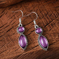 A pair of geometric vintage earrings with a black and purple electroplated finish, showing a pendant design with round elements.