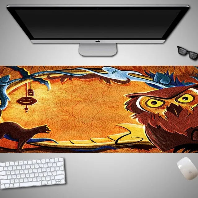 Oversized black Halloween-themed mouse pad with spooky artwork on a desk next to a gaming mouse.