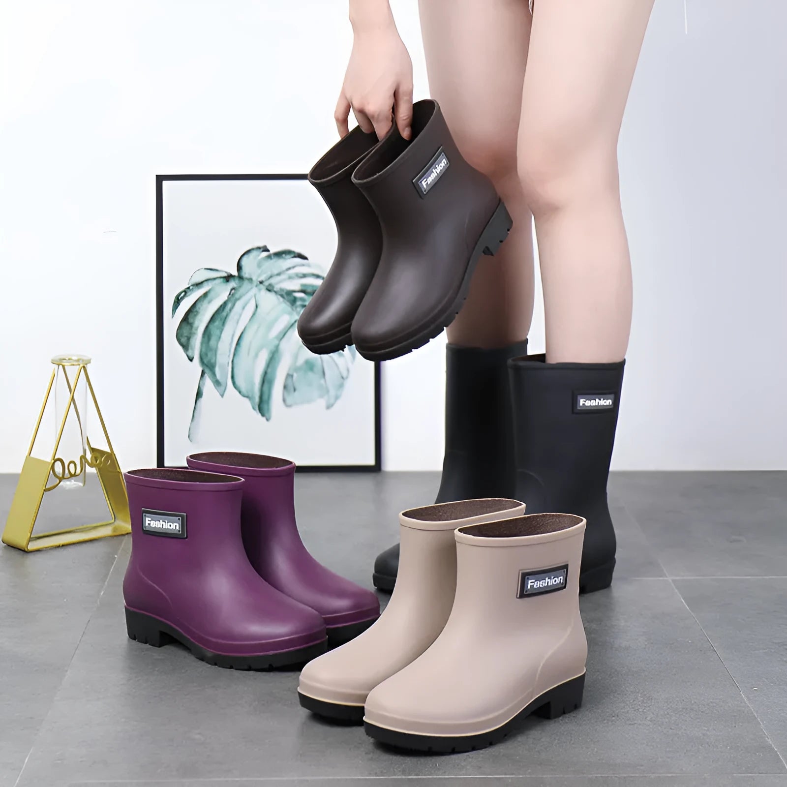 Women's mid-calf PVC rain boot in black on a wet surface, showing low heel and clean design.