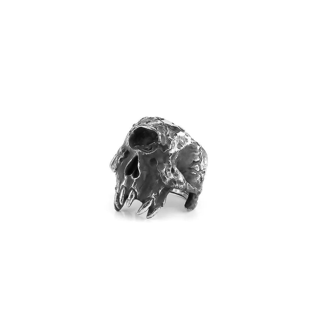 A silver-toned alloy ring with a raised one-eyed skull design on a black background.
