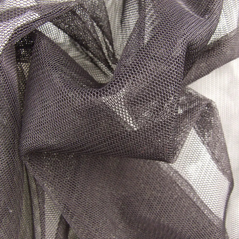 Adult wearing a light grey mesh anti-mosquito suit with hood, full-length pants, and booties for outdoor protection.