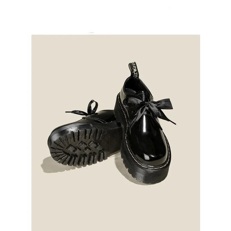 Women's black thick-soled lace-up shoes with ribbon and cross-strap design on a white background.