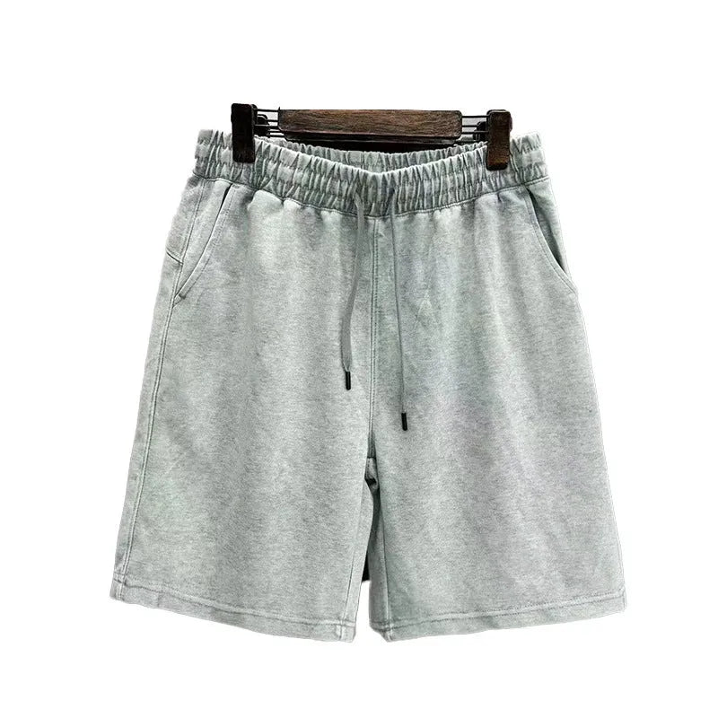 Man wearing charcoal black distressed cotton casual shorts with a loose straight fit.