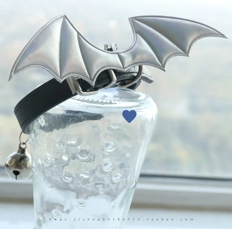 Small black patent leather dog collar with little devil wings charm and bell attached.