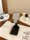 Folding plastic mobile phone stand in pearl white on a flat surface