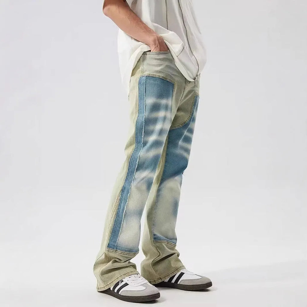 Yellow and blue retro patchwork jeans with splash-ink distressed detailing, showing mid waist and zip fly.
