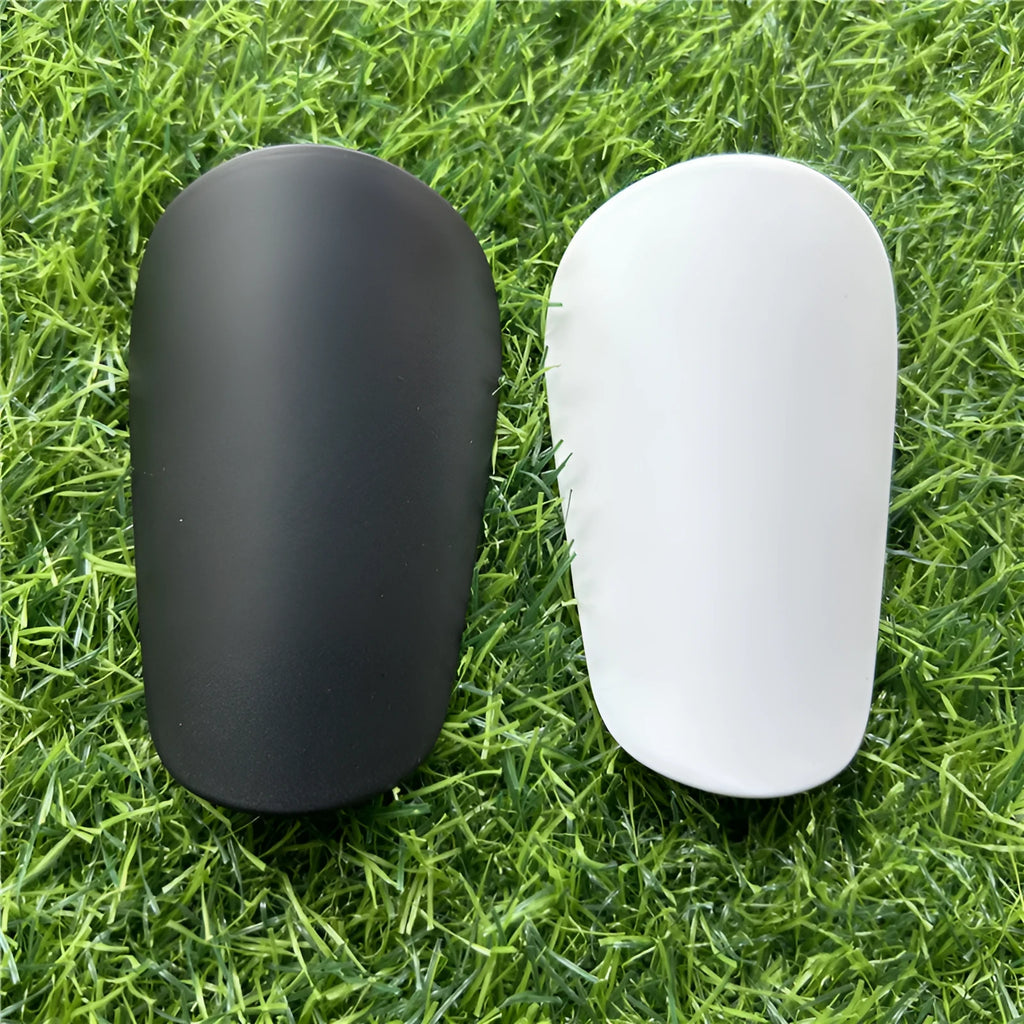 Extra small black and white plastic football shin guards for youth players, size 8cm by 5cm.