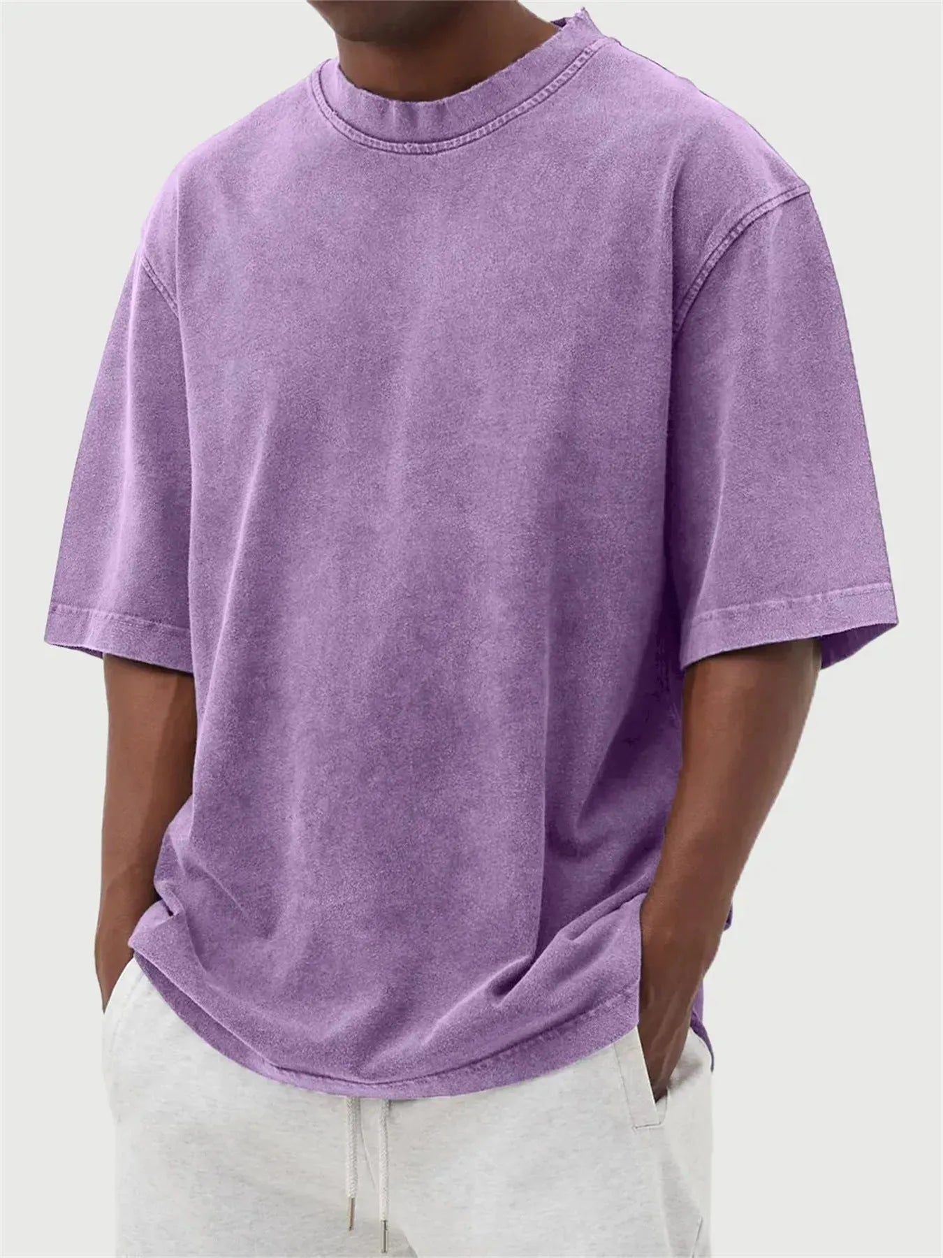 Man wearing a loose-fit, stone-washed grey t-shirt with a distressed solid colour finish and half sleeves.