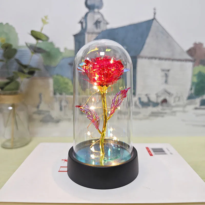 Small decorative table lamp with coloured LED lights illuminating plastic flowers under a glass dome.