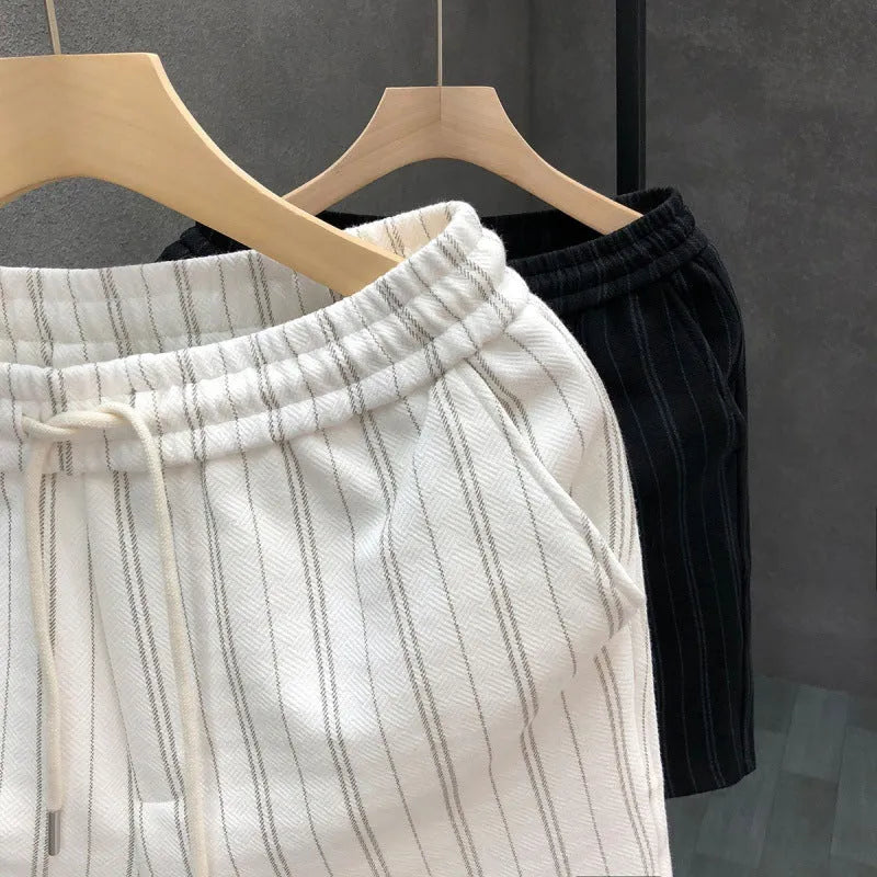 Men's black and white striped fleece-lined casual shorts with an ankle-banded cuff on a hanger.