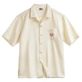 Light apricot men's shirt with bamboo plant print and a Cuban collar on a hanger