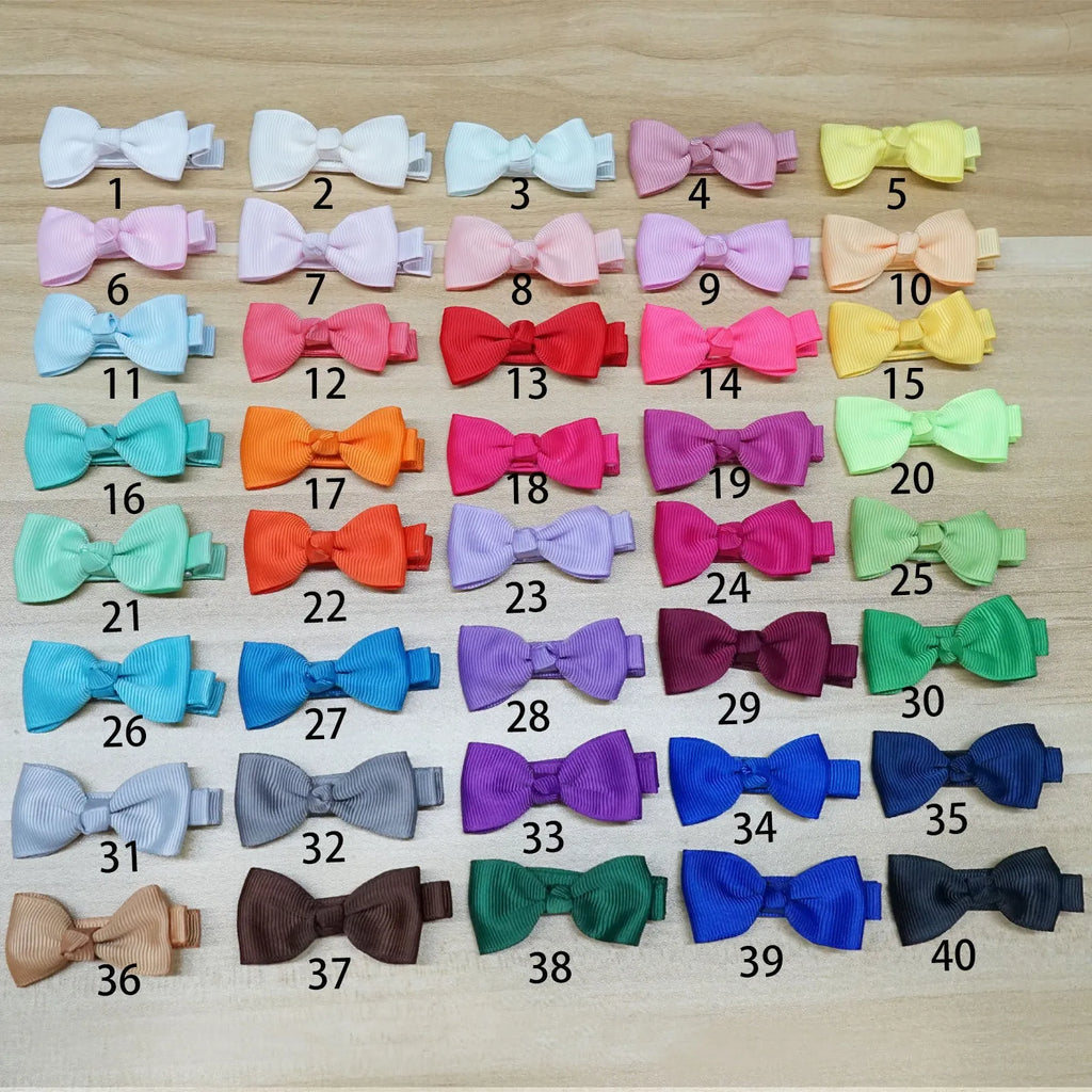 Assortment of pastel-coloured hair clips and bows for babies and toddlers on a white background.