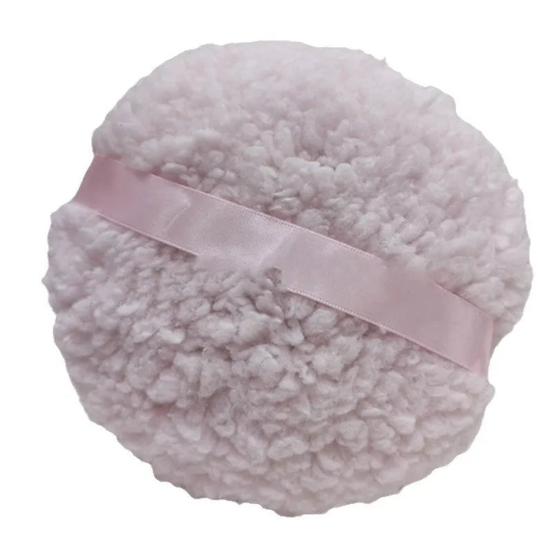 Oversized rectangular plush powder puff in white on a pink background.