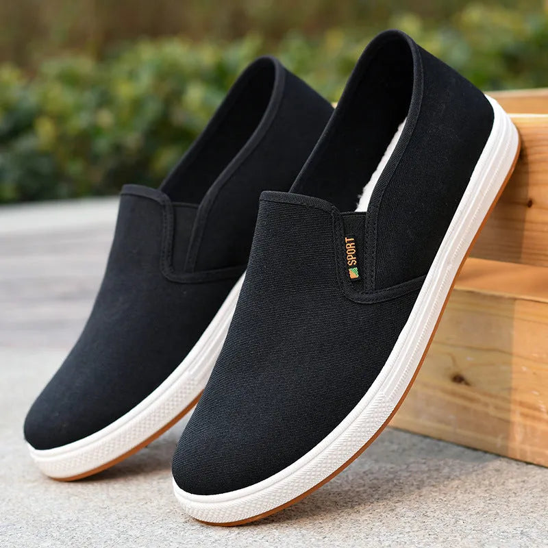 Men's low-top slip-on canvas shoe in blue on a white background, showing round toe and shallow mouth design.