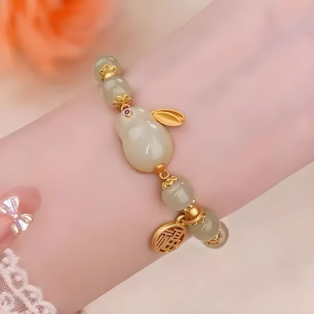 Green jade lucky bracelet with black hare charm, fu character, and lily flower on black adjustable cord.