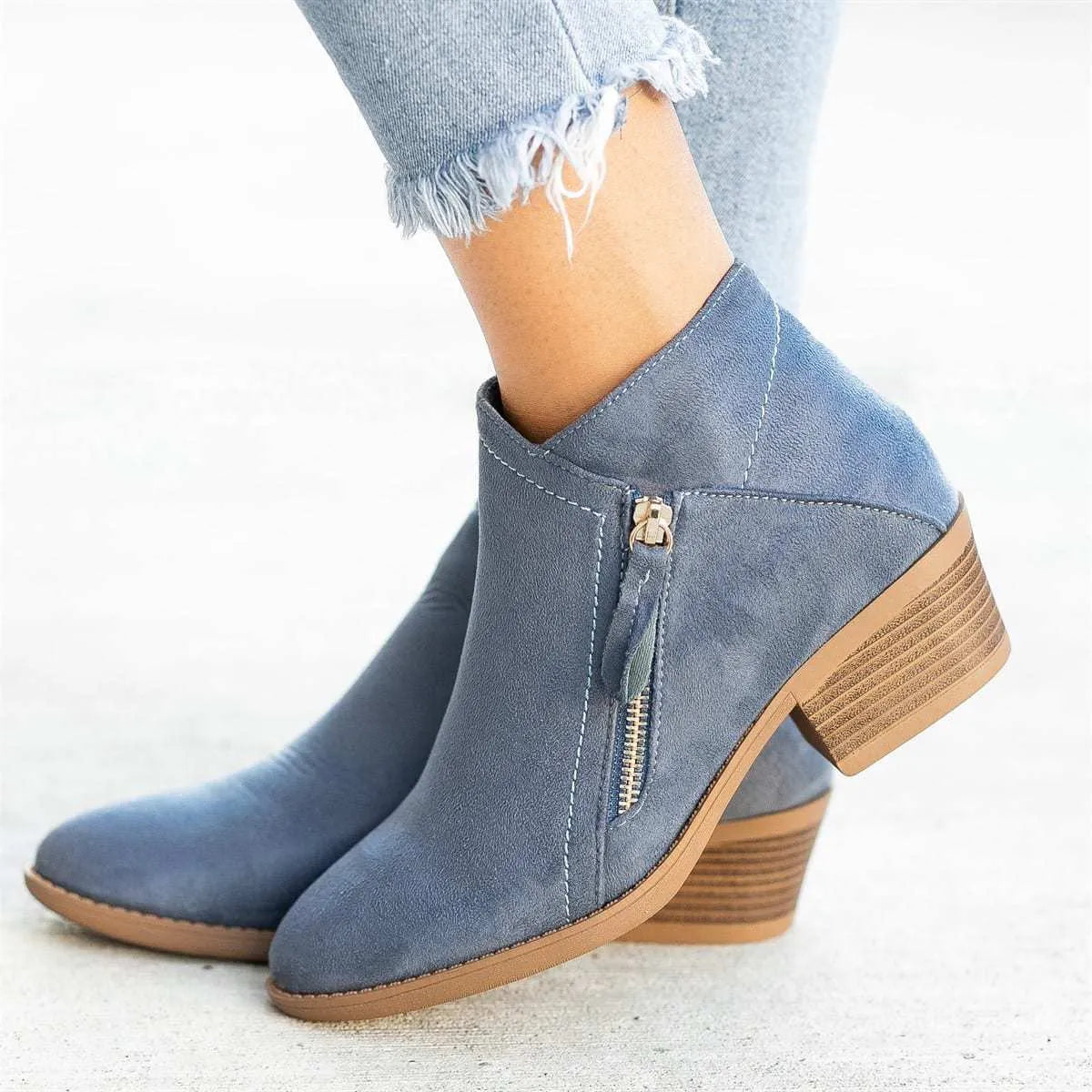 Blue Dr Martens women's suede ankle boots with a side zip and chunky heel on a white background.