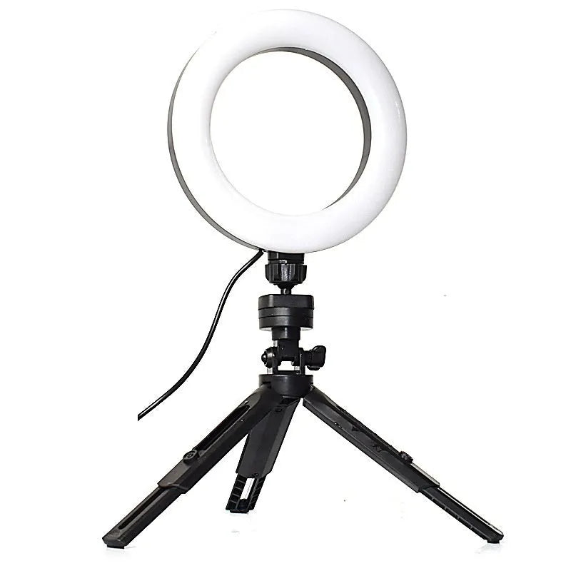 Black desktop tripod with adjustable fill light attached, holding a smartphone for streaming or video calls.