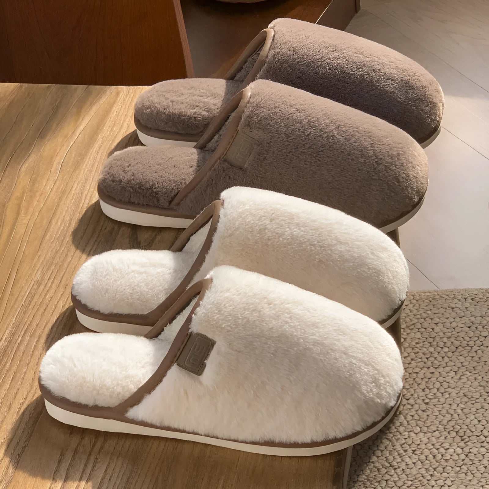 Pair of solid colour plush house slippers with PVC sole on a wooden floor.
